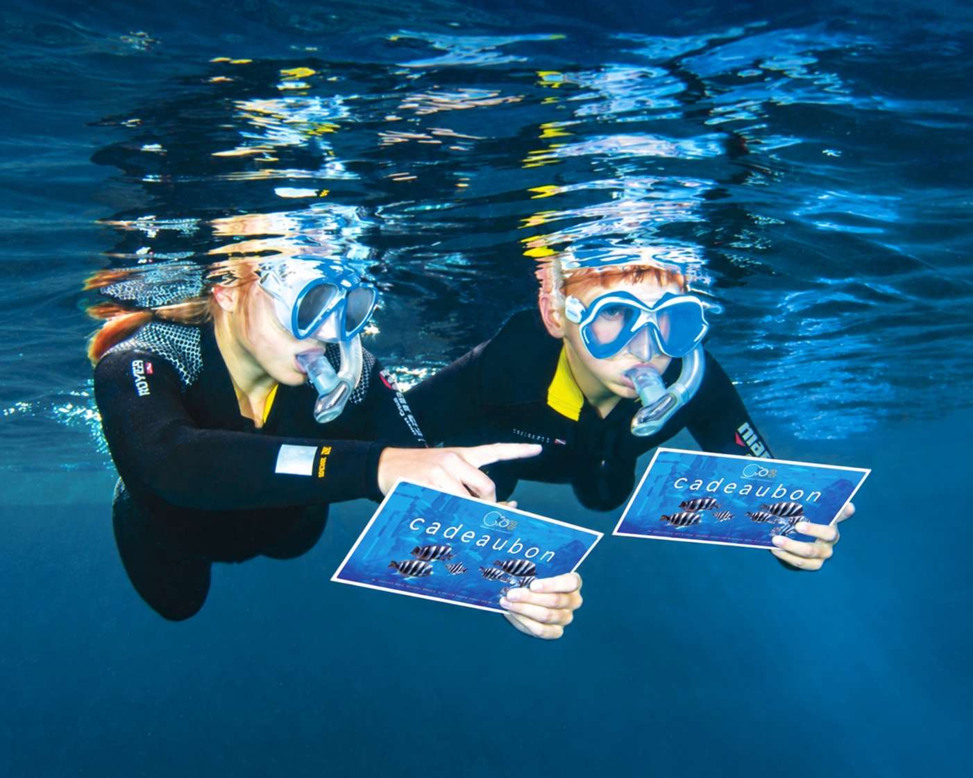 Twee snorkelaars onder water met TODI-cadeaubonnen in hun handen.